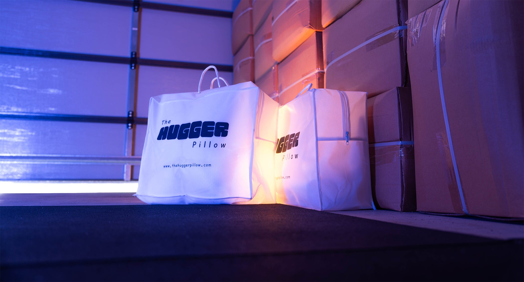 This is a banner image on the Shipping and Returns page, showing two Hugger Pillow packages in a warehouse or garage